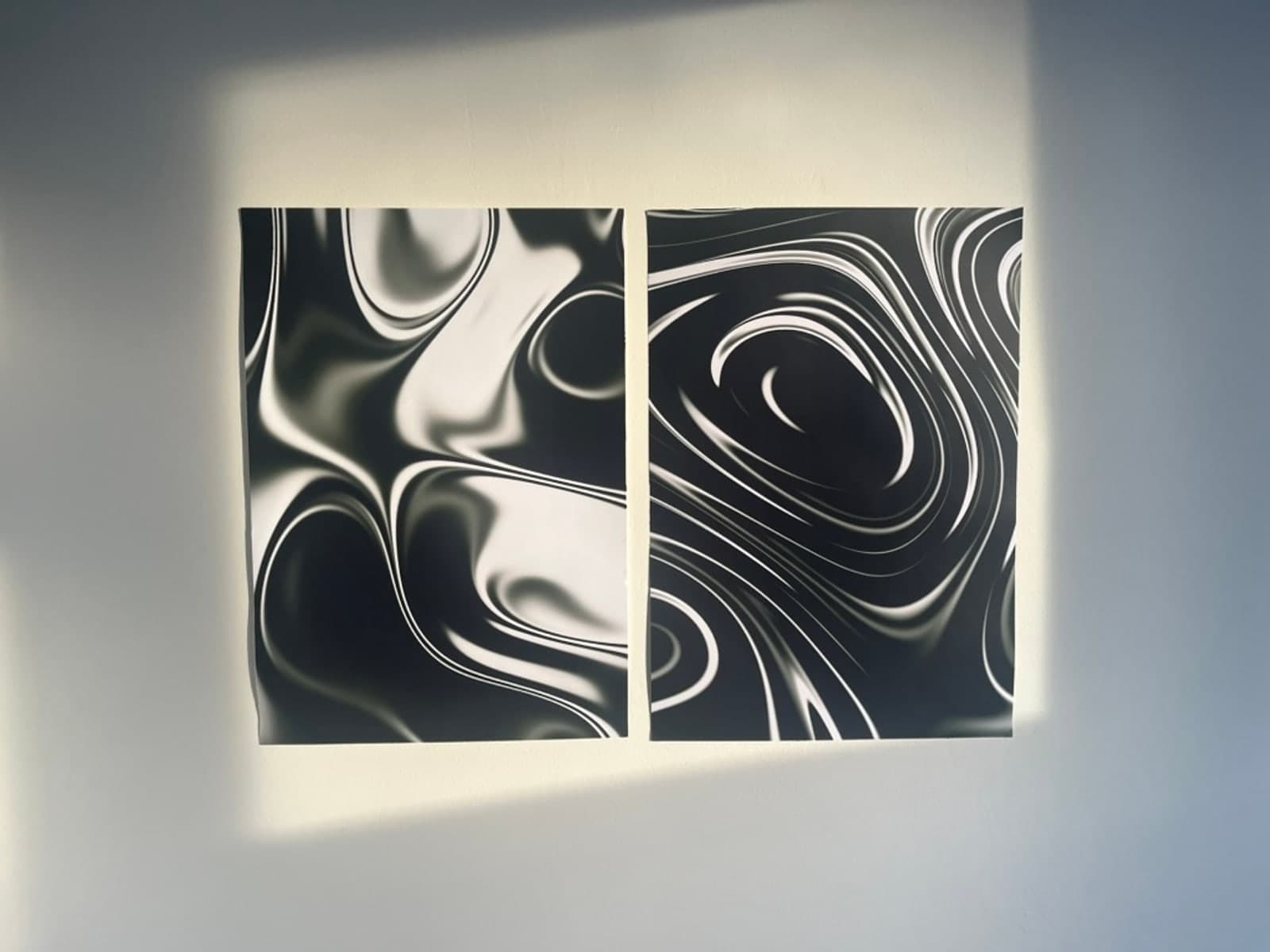 Two black-and-white generative prints pinned to a wall.